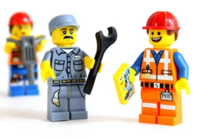 Drei Klemmbausteinfiguren mit Werkzeugen